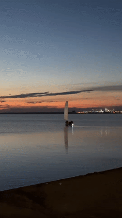 Sailboat on calm Kazakh lake waters at dusk