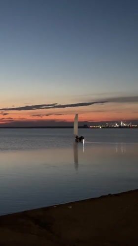 Sailboat on calm Kazakh lake waters at dusk