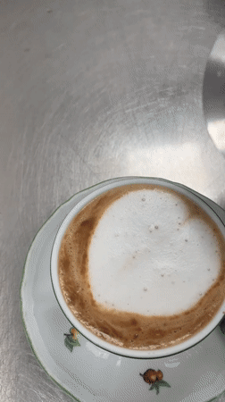Latte pour into a floral cup in a Tuscan café