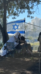 People gather in Tel Aviv park with signature-covered flag