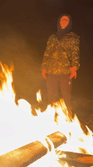 Man tends bonfire during snowfall in Russian village