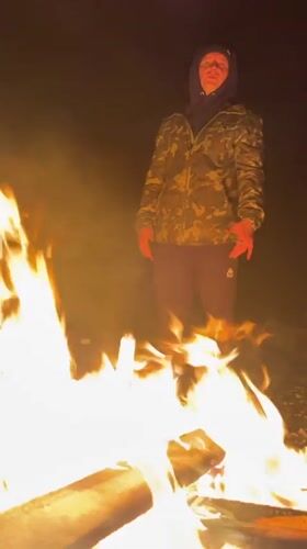 Man tends bonfire during snowfall in Russian village