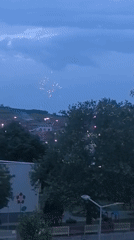 Pink fireworks light up twilight sky over city
