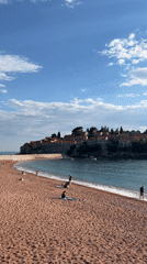 Tourists enjoy sunny afternoon at Sveti Stefan beach Montenegro