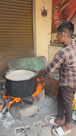 Man tends boiling pot over wood fire in Bengaluru
