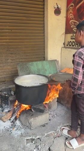 Man tends boiling pot over wood fire in Bengaluru