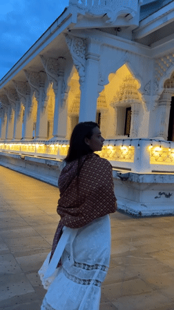 Woman photographed at illuminated Thai temple during evening visit