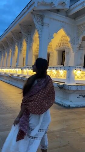 Woman photographed at illuminated Thai temple during evening visit