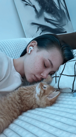 Woman naps with orange kitten on couch in Khimki
