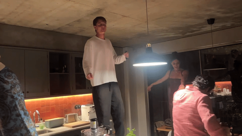 Standing on a kitchen counter, gesturing to a crowd