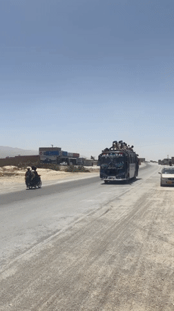 Overloaded passenger bus travels dusty road in Pakistan