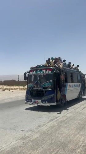 Overloaded passenger bus travels dusty road in Pakistan