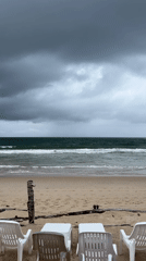 Stormy beach scene captured with furniture, walkers during overcast morning