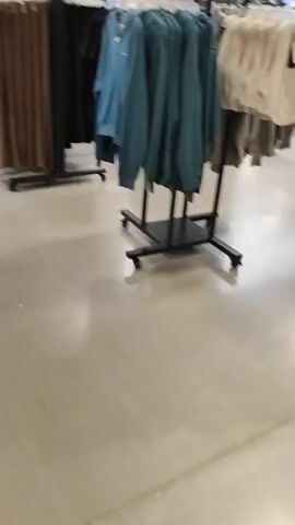 The video shows a person walking through a retail store, possibly a shoe store. The aisles are lined with shelves filled with orange shoe boxes. Several pairs of shoes are displayed on shelves, and a large mirror is leaning against a display. The store appears to be well-stocked and organized. The video captures close-ups of shoe displays and the general layout of the store.
