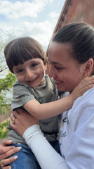 Woman and child share moment outside building in Arinj