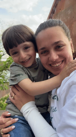 Woman and child share moment outside building in Arinj
