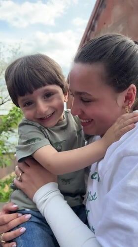 Woman and child share moment outside building in Arinj