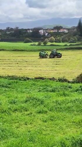 Tractor bales hay in fields near Ribeira Grande