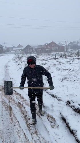 Man shovels sawdust during heavy snowfall near Sarapul, Russia
