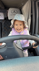 Toddler poses at steering wheel during family stop in Poland