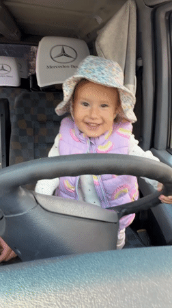 Toddler poses at steering wheel during family stop in Poland