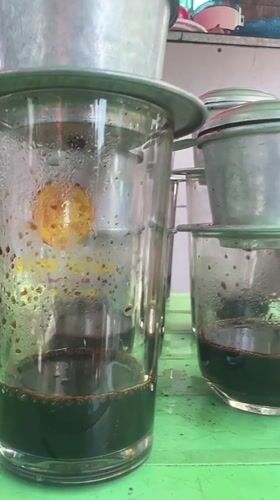 Vietnamese street vendor serves traditional drip coffee in morning setup