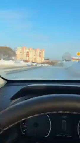 Here's a description of the video:
The video is taken from the inside of a car. Initially, the view is focused on the dashboard, the windshield, and a white surface outside, possibly a truck or building. The camera then shifts to a young man wearing a black beanie and a white puffer jacket with the word "RIDE" on it. He looks directly at the camera and then glances to his right. The video then pans back to the car's interior, showing the infotainment screen, the climate control buttons, and the dashboard. Finally, the view shifts to the steering wheel and the car's digital instrument cluster, which displays information about the vehicle. The weather outside appears to be sunny.