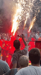 Street parade with red costumes, flares, and a dragon float
