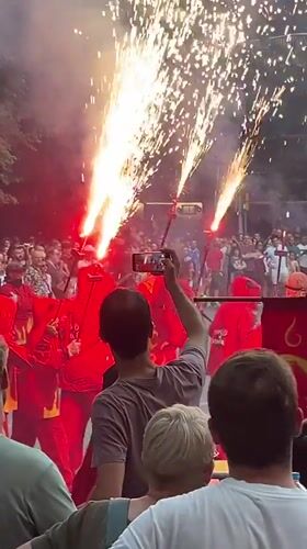 Street parade with red costumes, flares, and a dragon float