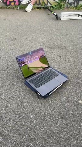 A laptop shows a soccer video game on its screen. The laptop sits on the ground in a carrying case. The screen then shows a close up of an in-game shot on goal. The laptop then falls to the ground after being kicked by a scooter. A man then drinks from a can of AriZona brand iced tea.
