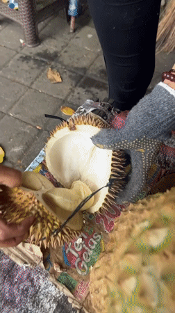 Man enjoys durian fruit at roadside vendor in Indonesia