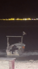 Nighttime scenes captured: beached boat, man using phone in Indonesia