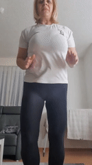Woman performs indoor exercise routine in white shirt