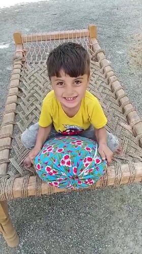 Child plays on traditional bed in Pakistani village courtyard