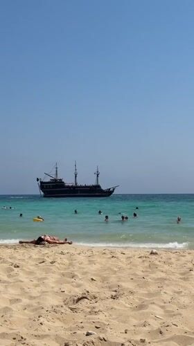 Sunny day at Nissi Beach, Ayia Napa, pirate ship offshore
