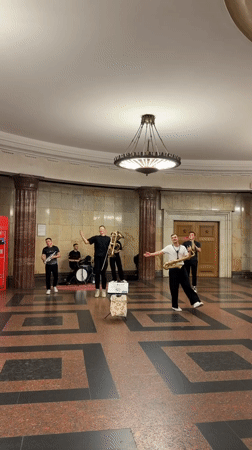 Live band plays Moscow's ornate public interior, surfing mural nearby