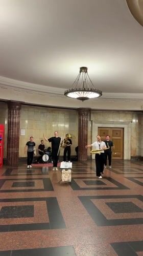 Live band plays Moscow's ornate public interior, surfing mural nearby
