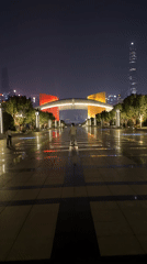 Man walks wet pathway near lit archway in Futian