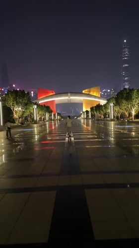 Man walks wet pathway near lit archway in Futian