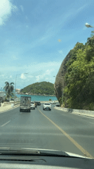 Vehicle captures sunny coastal road view in Thailand