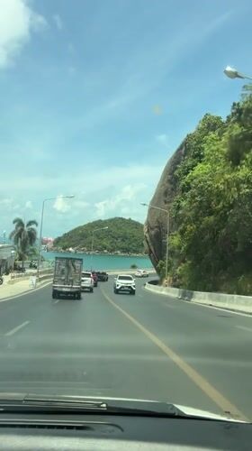 Vehicle captures sunny coastal road view in Thailand