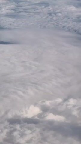 The video shows an aerial view of clouds. The clouds appear to be white and grey and are layered. The camera is looking down at the clouds from above. The video is shot in landscape orientation.