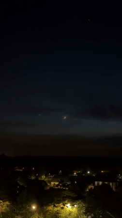 Crescent moon and light phenomena observed over residential area