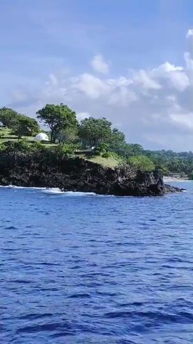 People gather on rocky coastline near tents in Karangasem