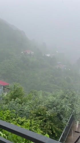 Rainy balcony view over Batumi's green hillside