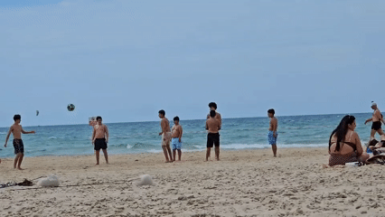 Crowded beach draws sunbathers, soccer players during sunny morning