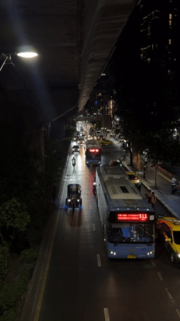 Evening traffic flows through wet Bangkok streets near Petchaburi intersection