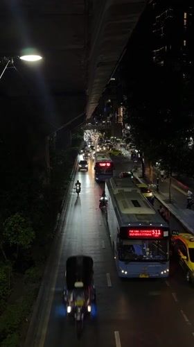 Evening traffic flows through wet Bangkok streets near Petchaburi intersection