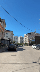 Busy street scene with shops, cafés, and mixed traffic on a sunny day