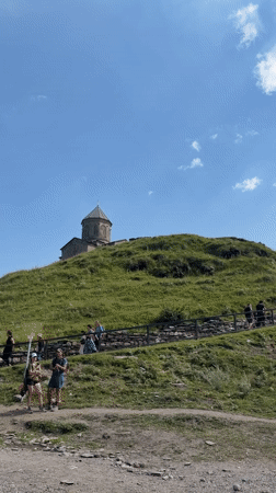 Hilltop church and grazing horse in Stepantsminda's mountain valley